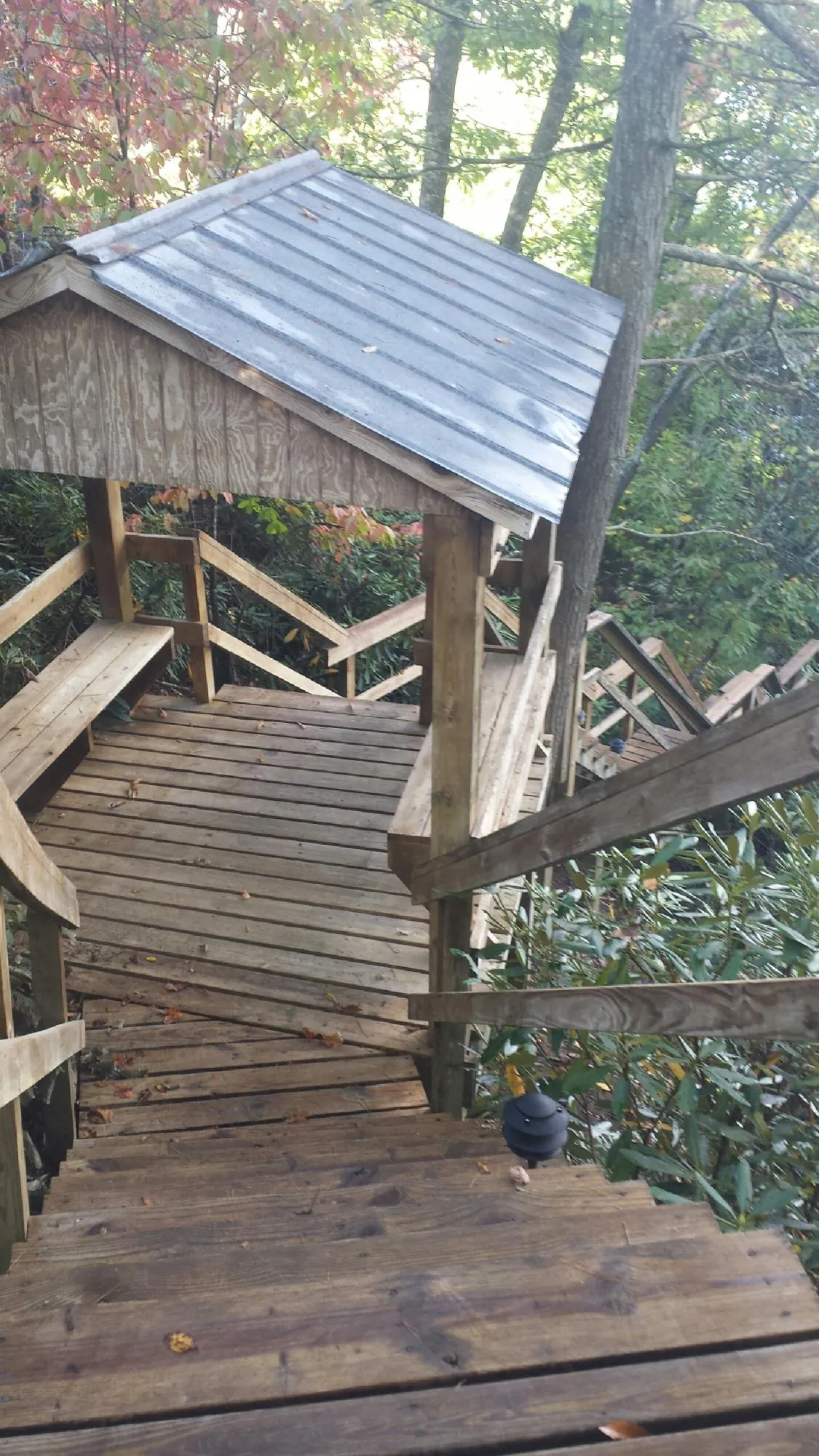 Metal roofed shelter over wooden steps on a wooded walkway — Skylight Repair & Installation work by our crew in Rock Island