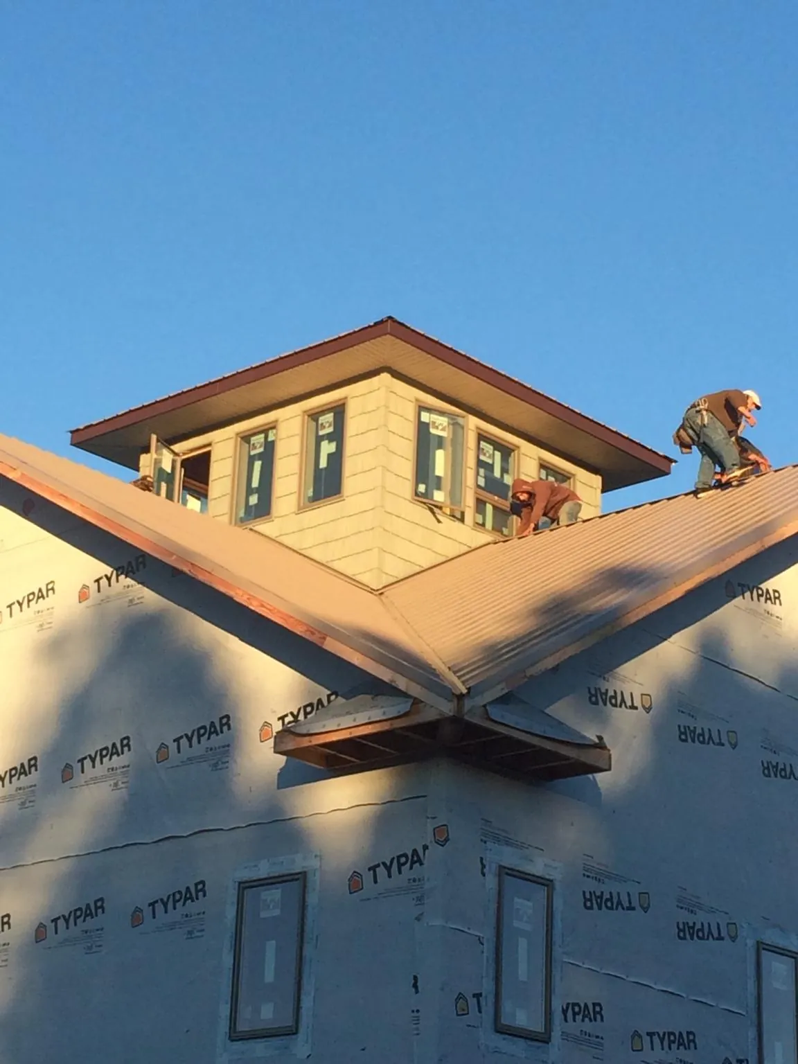 Roofers working around a rooftop cupola on a new metal roof at sunset — Roof Waterproofing in Rock Island by Roofing Brothers